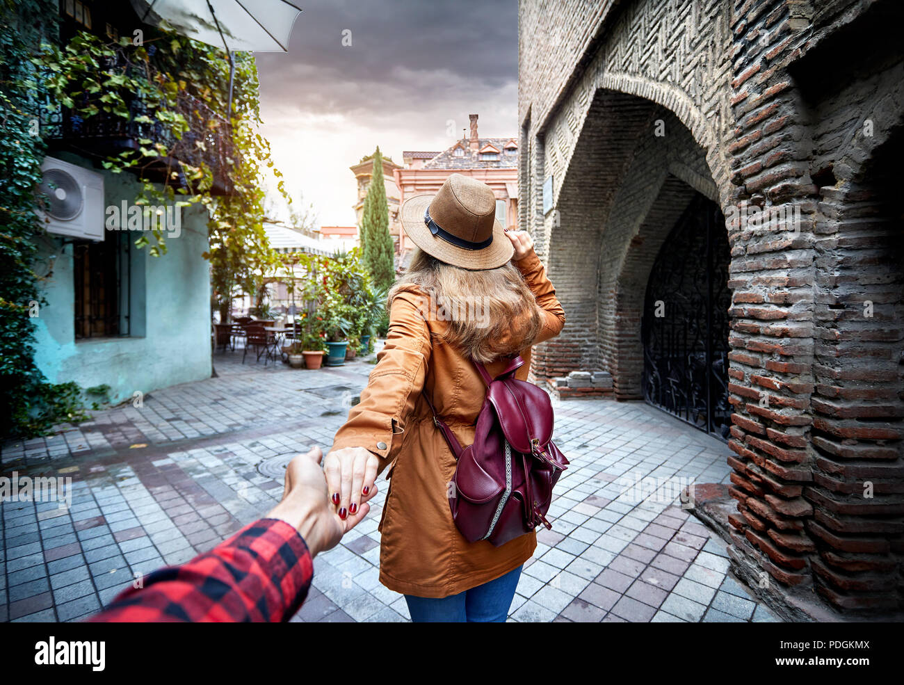 La donna nel cappello e giacca marrone che conduce l uomo della strada stretta nella vecchia, Georgia Foto Stock