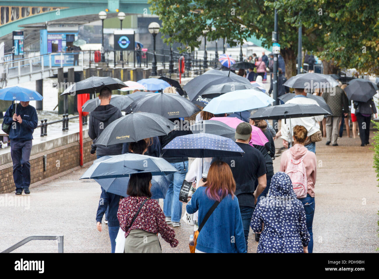 Bankside, Londra, Regno Unito. Il 9 agosto, 2018. I londinesi di ottenere i loro ombrelli e impermeabili come pioggia e temperature più basse sostituire la recente ondata di caldo. Michael Heath/Alamy Live News Foto Stock