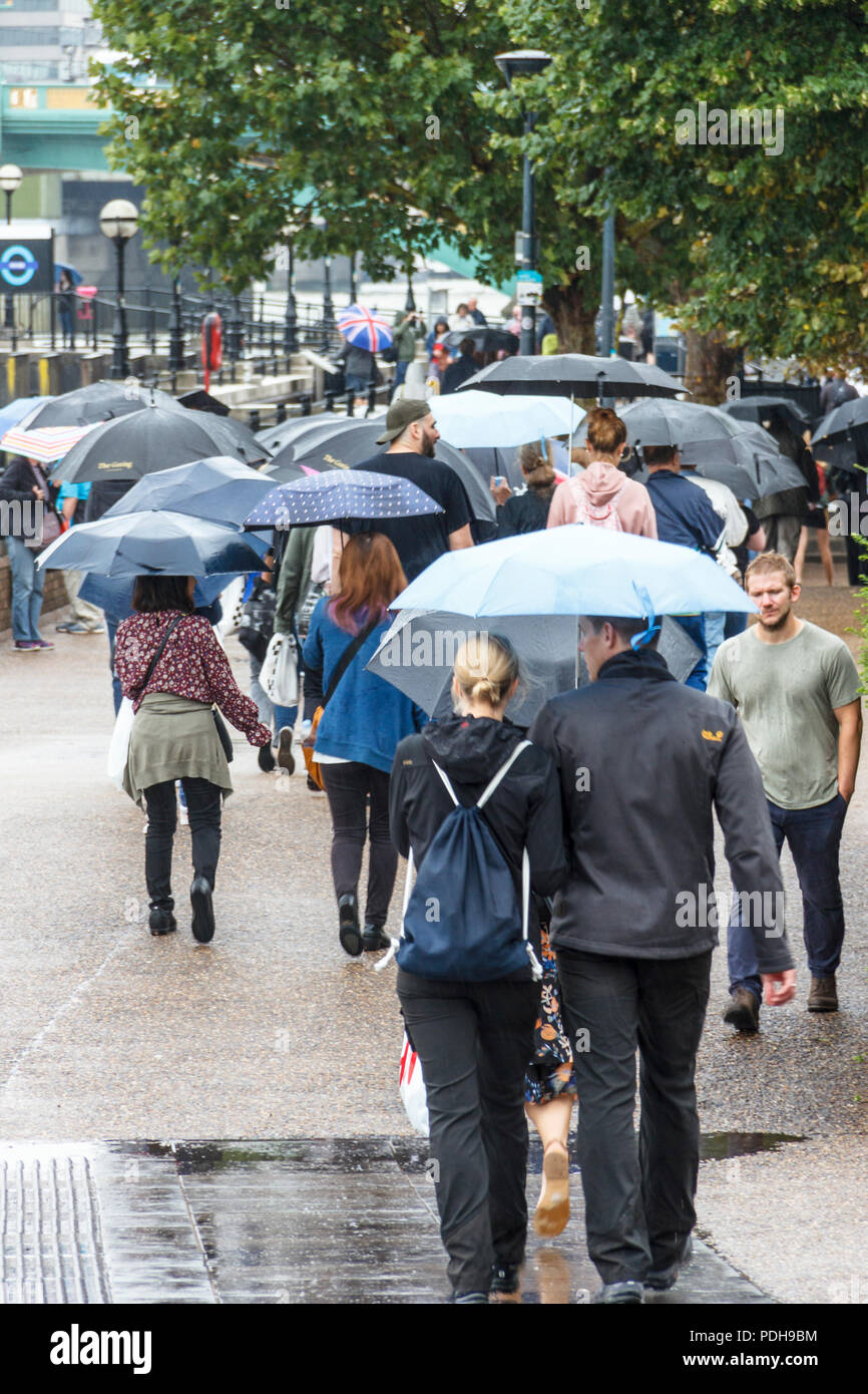 Bankside, Londra, Regno Unito. Il 9 agosto, 2018. I londinesi di ottenere i loro ombrelli e impermeabili come pioggia e temperature più basse sostituire la recente ondata di caldo. Michael Heath/Alamy Live News Foto Stock