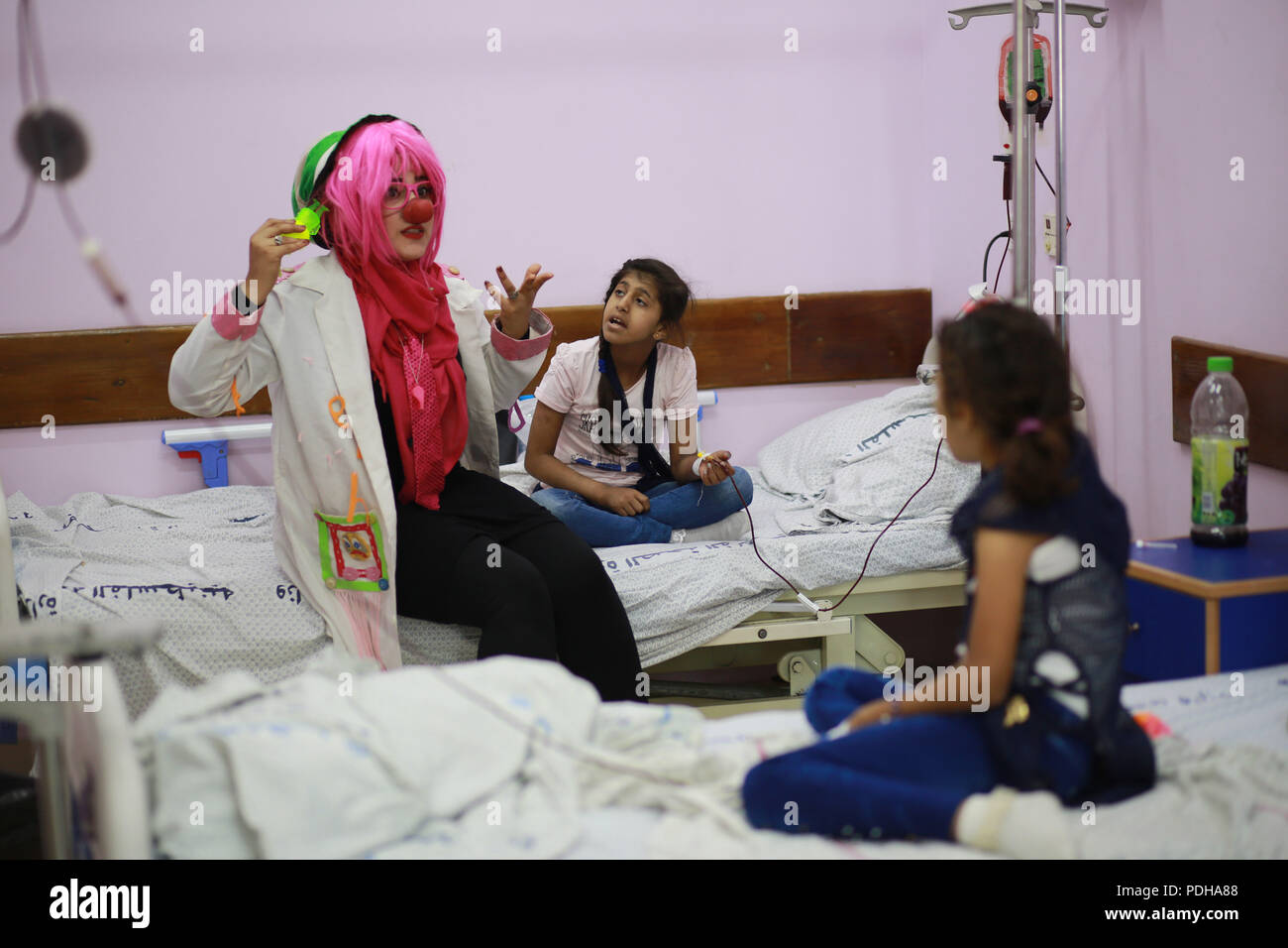 La striscia di Gaza. Il 9 agosto, 2018. Dina Nassar (1L), intrattiene i bambini che sono i pazienti malati di cancro, nel suo costume da clown all'interno di un ospedale di Gaza City, e il Agosto 8, 2018. Cinque anni fa dopo il Dina's padre morì di cancro, ha iniziato a fare del volontariato in Basmit Amal associazione, una fondazione per la cura del cancro, servizio nella Striscia di Gaza. Ora Dina Nassar e un intero team di volontari svolgono i clown nel loro tempo libero per disegnare un sorriso ai bambini, labbra. Credito: Xinhua/Alamy Live News Foto Stock