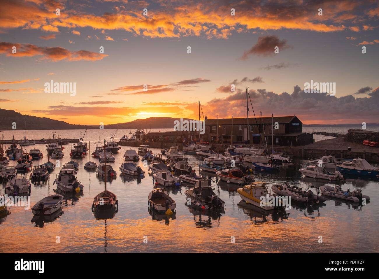 Lyme Regis, Dorset, Regno Unito. Il 10 agosto 2018. Regno Unito: Meteo spettacolare alba colori alla città costiera di Lyme Regis. Il cielo sopra lo storico porto di Cobb si illumina di rosso e arancio in anticipo dei temporali e acquazzoni. Credito: Celia McMahon/Alamy Live News. Foto Stock