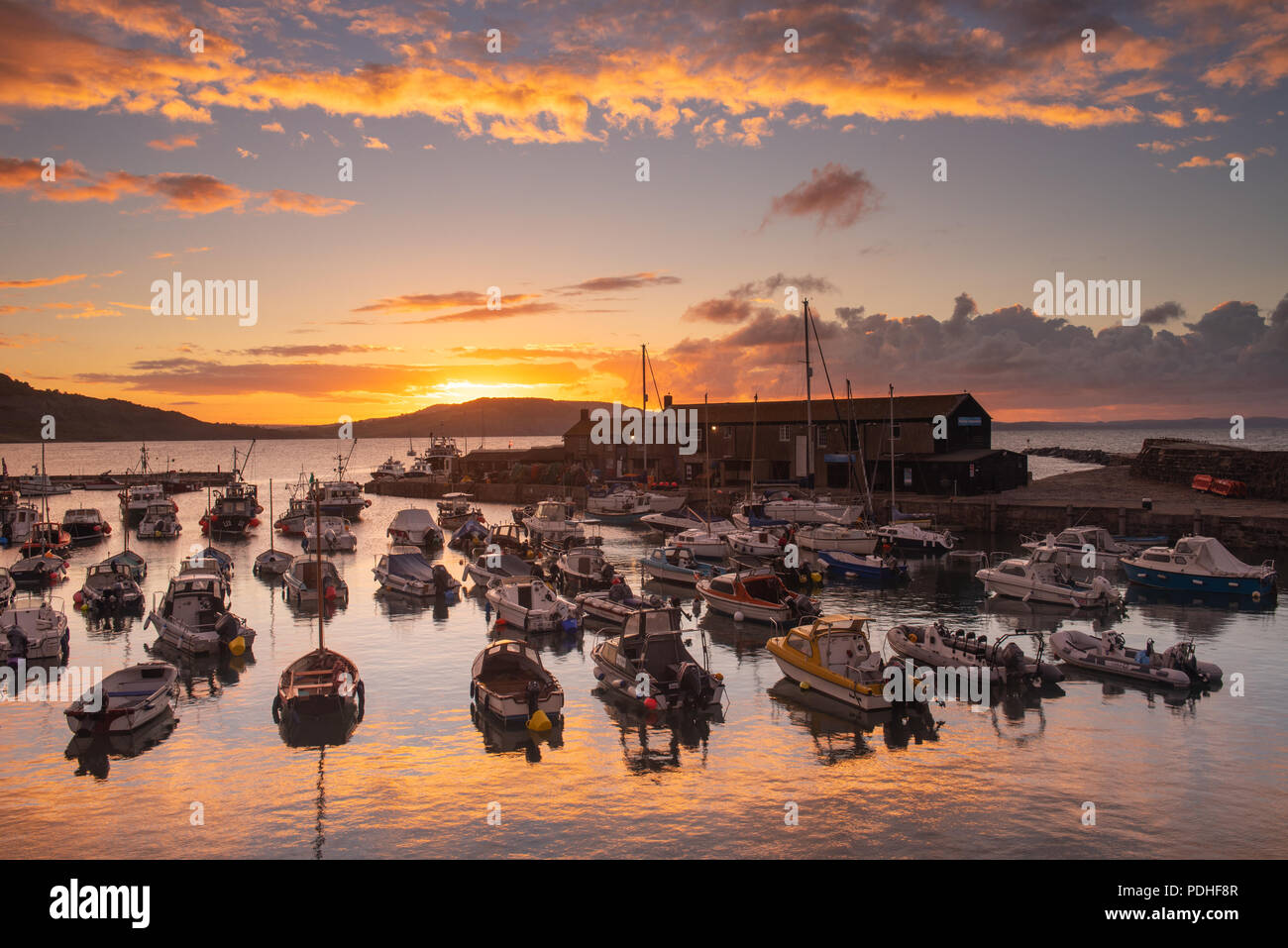 Lyme Regis, Dorset, Regno Unito. Il 10 agosto 2018. Regno Unito: Meteo spettacolare alba colori alla città costiera di Lyme Regis. Il cielo sopra lo storico porto di Cobb si illumina di rosso e arancio in anticipo dei temporali e acquazzoni. Credito: Celia McMahon/Alamy Live News. Foto Stock