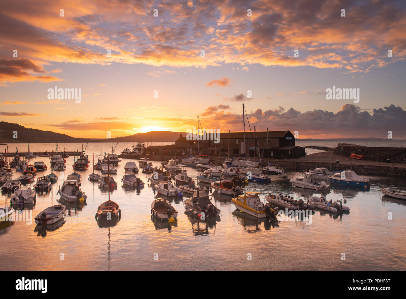 Lyme Regis, Dorset, Regno Unito. Il 10 agosto 2018. Regno Unito: Meteo spettacolare alba colori alla città costiera di Lyme Regis. Il cielo sopra lo storico porto di Cobb si illumina di rosso e arancio in anticipo dei temporali e acquazzoni. Credito: Celia McMahon/Alamy Live News. Foto Stock