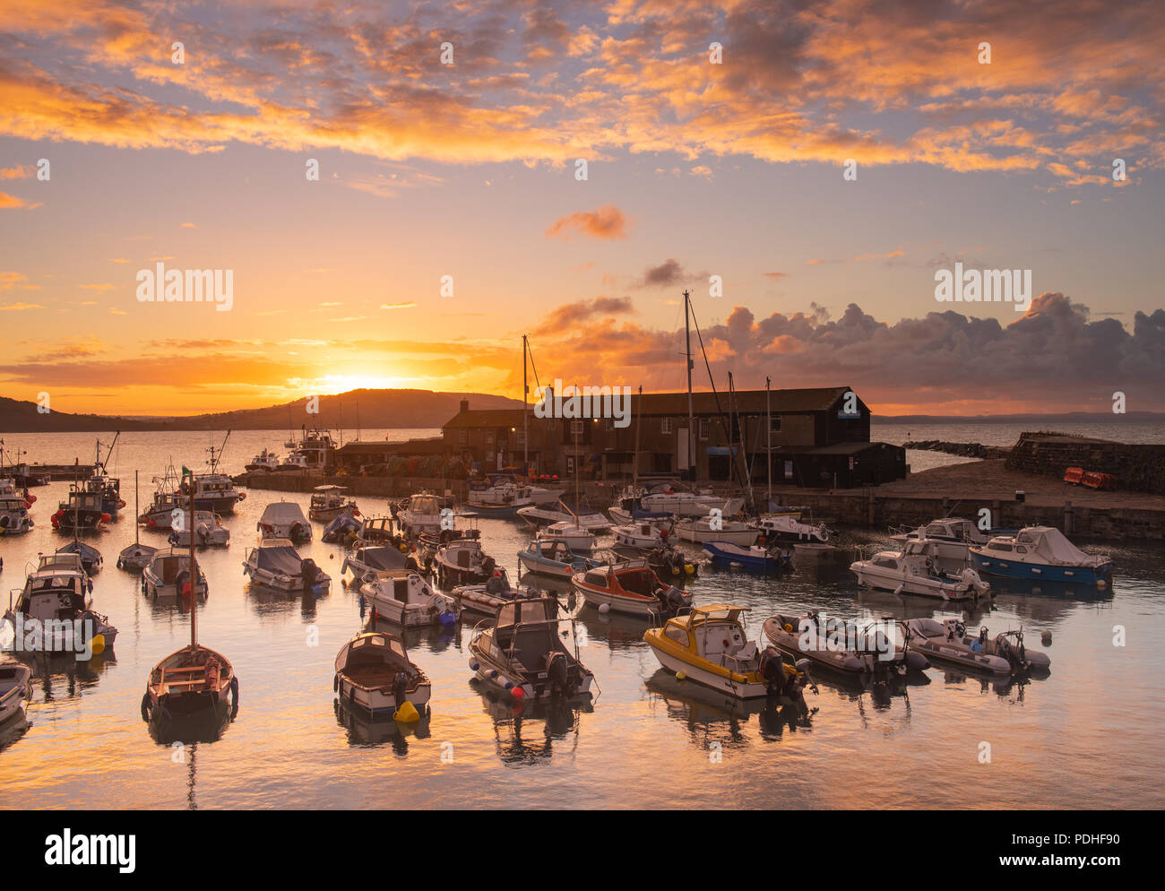 Lyme Regis, Dorset, Regno Unito. Il 10 agosto 2018. Regno Unito: Meteo spettacolare alba colori alla città costiera di Lyme Regis. Il cielo sopra lo storico porto di Cobb si illumina di rosso e arancio in anticipo dei temporali e acquazzoni. Credito: Celia McMahon/Alamy Live News. Foto Stock