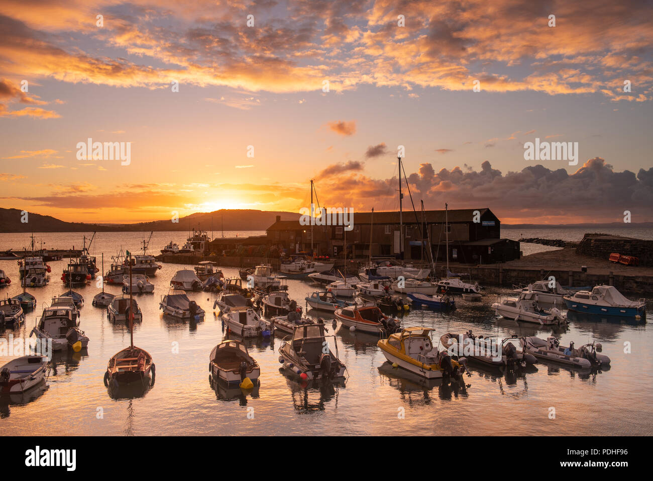 Lyme Regis, Dorset, Regno Unito. Il 10 agosto 2018. Regno Unito: Meteo spettacolare alba colori alla città costiera di Lyme Regis. Il cielo sopra lo storico porto di Cobb si illumina di rosso e arancio in anticipo dei temporali e acquazzoni. Credito: Celia McMahon/Alamy Live News. Foto Stock