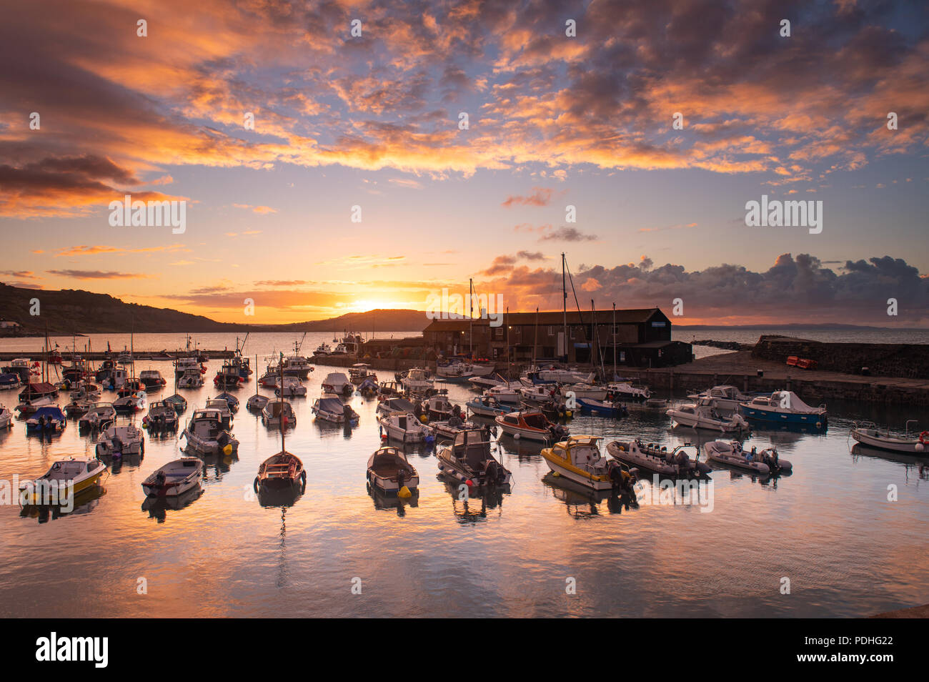 Lyme Regis, Dorset, Regno Unito. Il 10 agosto 2018. Regno Unito: Meteo spettacolare alba colori alla città costiera di Lyme Regis. Il cielo sopra lo storico porto di Cobb si illumina di rosso e arancio in anticipo dei temporali e acquazzoni. Credito: Celia McMahon/Alamy Live News. Foto Stock