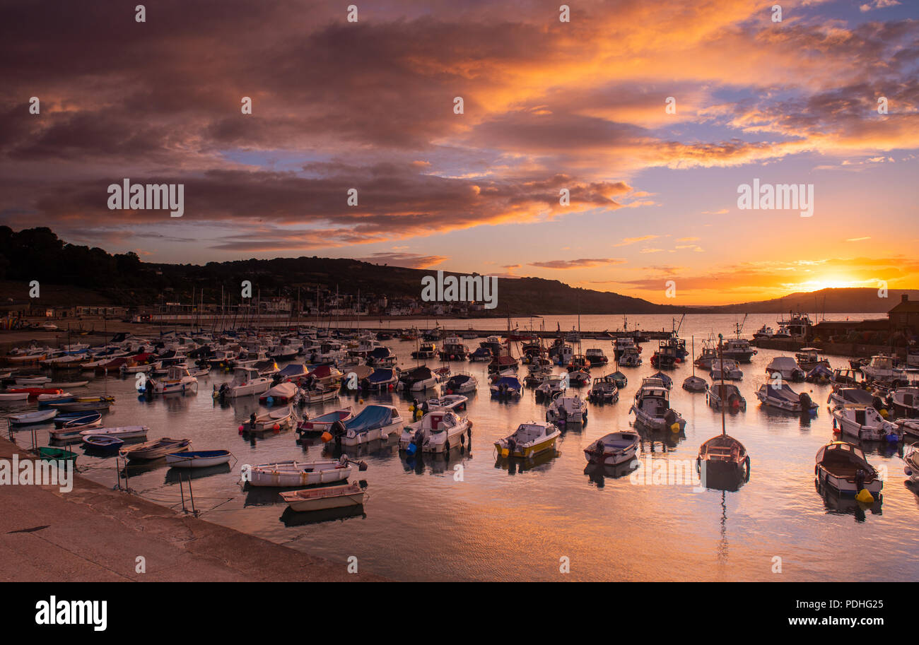 Lyme Regis, Dorset, Regno Unito. Il 10 agosto 2018. Regno Unito: Meteo spettacolare alba colori alla città costiera di Lyme Regis. Il cielo sopra lo storico porto di Cobb si illumina di rosso e arancio in anticipo dei temporali e acquazzoni. Credito: Celia McMahon/Alamy Live News. Foto Stock