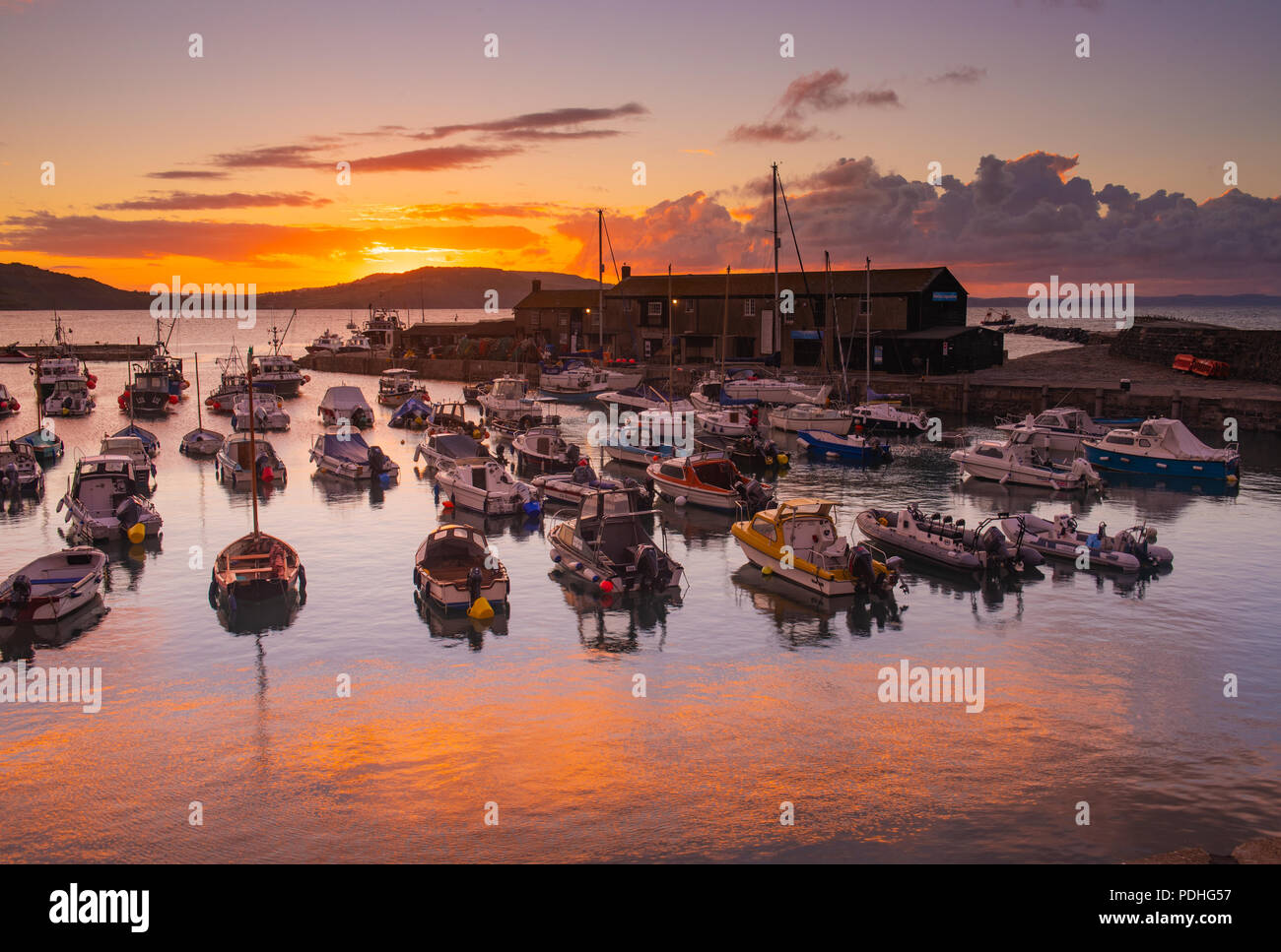 Lyme Regis, Dorset, Regno Unito. Il 10 agosto 2018. Regno Unito: Meteo spettacolare alba colori alla città costiera di Lyme Regis. Il cielo sopra lo storico porto di Cobb si illumina di rosso e arancio in anticipo dei temporali e acquazzoni. Credito: Celia McMahon/Alamy Live News. Foto Stock