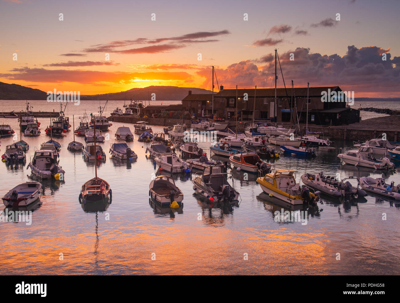 Lyme Regis, Dorset, Regno Unito. Il 10 agosto 2018. Regno Unito: Meteo spettacolare alba colori alla città costiera di Lyme Regis. Il cielo sopra lo storico porto di Cobb si illumina di rosso e arancio in anticipo dei temporali e acquazzoni. Credito: Celia McMahon/Alamy Live News. Foto Stock