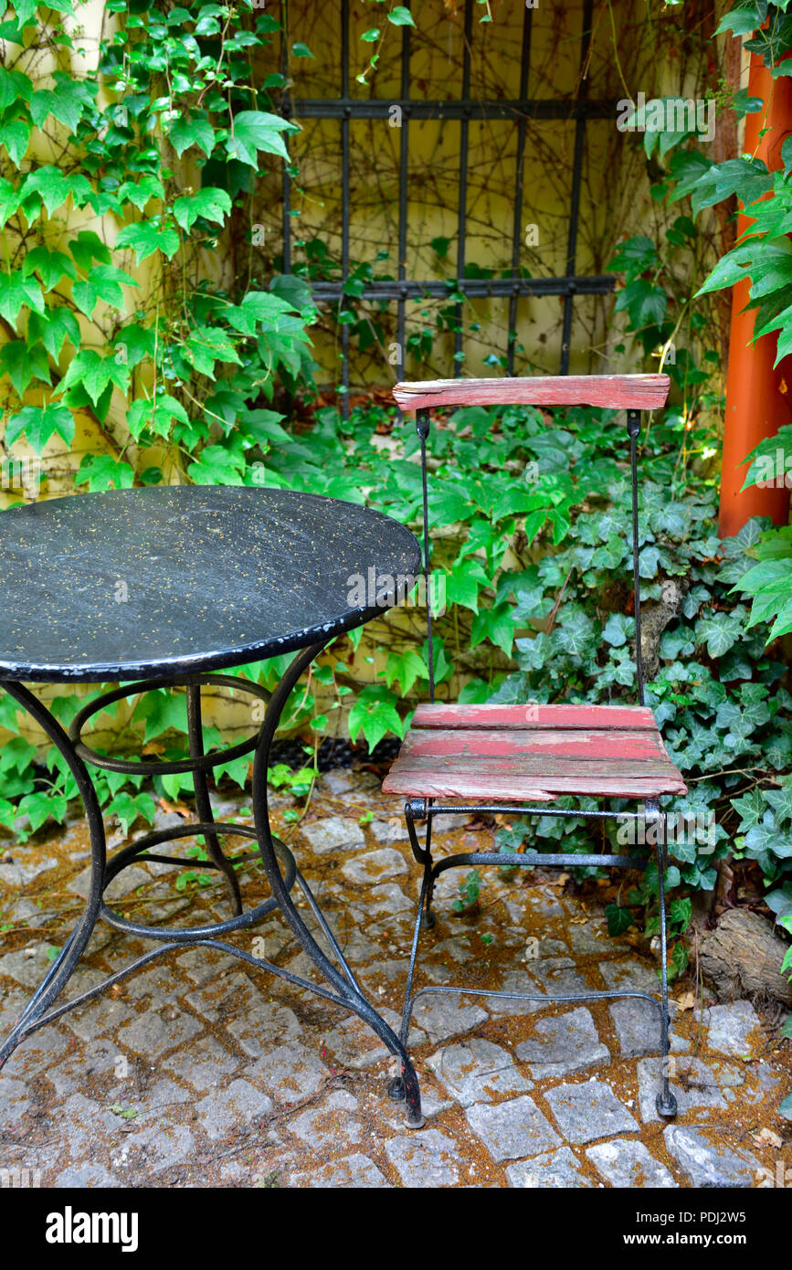Metallo vecchio tavolo e sedia da ivy patio coperto le pareti Foto Stock