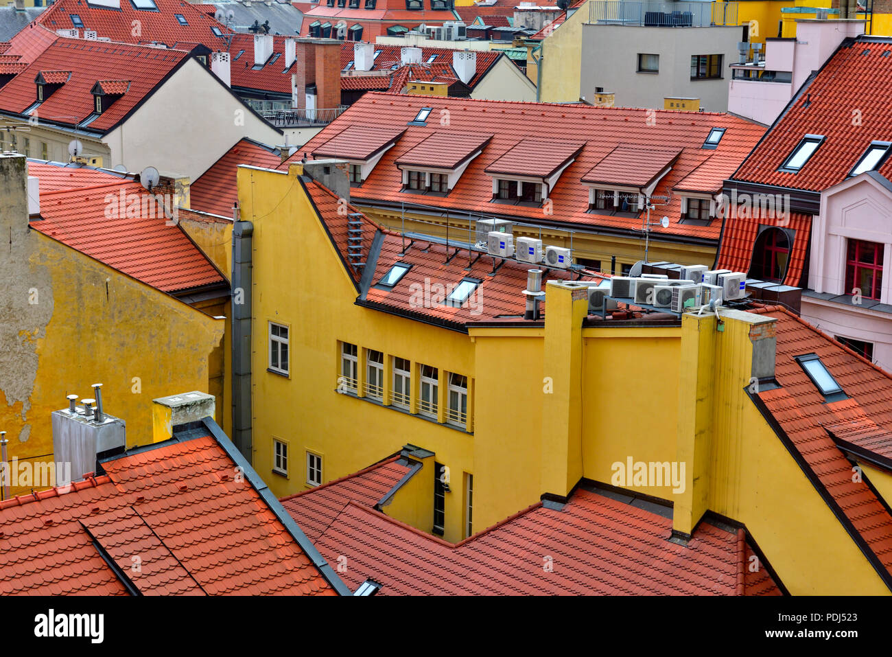 Tradizionale tetto di tegole rosse e cime di lucernari, abbaini e righe di aria condizionata di scambi di calore nella zona centrale di Praga, Repubblica Ceca Foto Stock