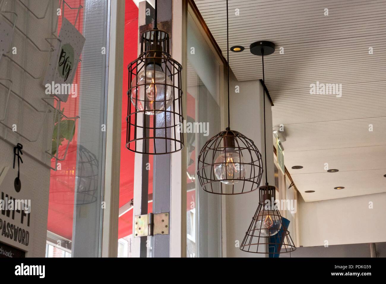 Le lampadine della luce in un filo metallico gabbia appesi al soffitto in un cafe Foto Stock