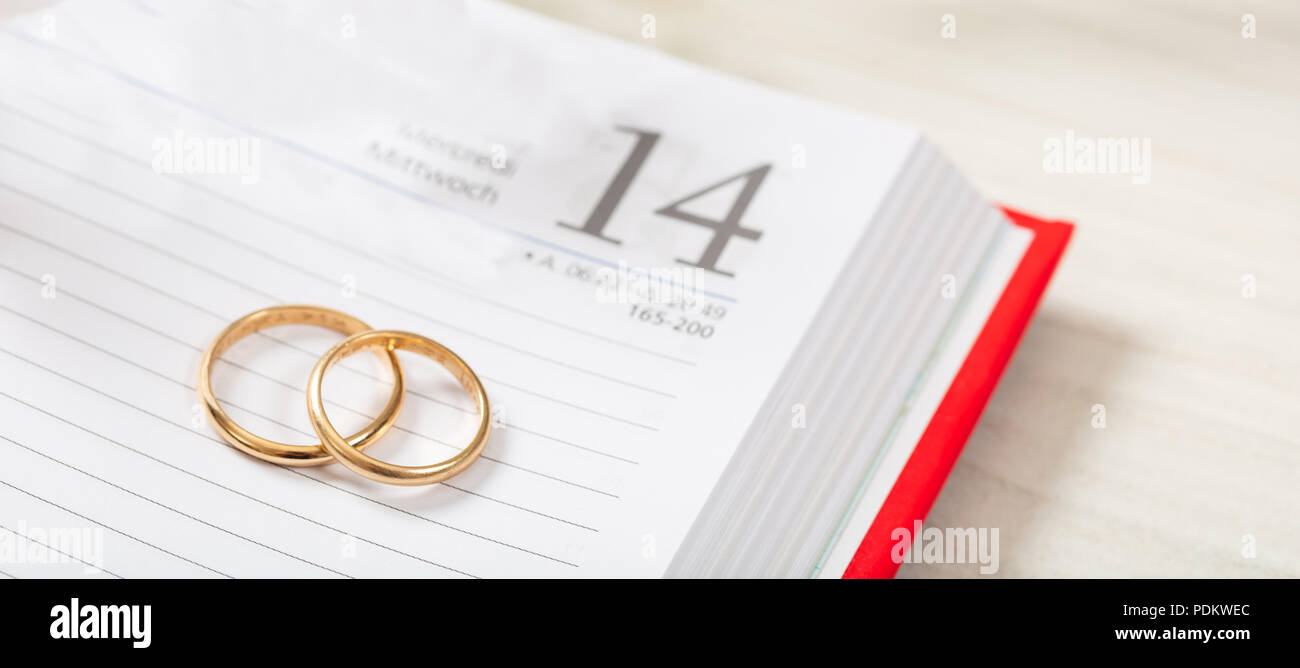 Pianificazione del concetto di matrimonio. Vista superiore del golden gli anelli di nozze su un calendario, su di un legno bianco tavolo. Foto Stock