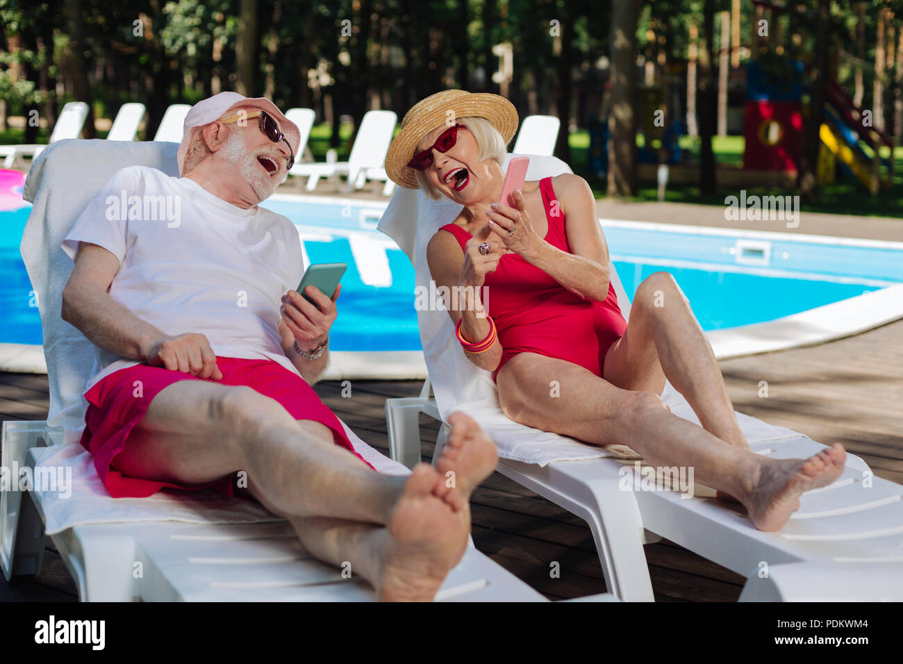 Moderno uomo maturo e la donna ridendo utilizzando i telefoni intelligenti Foto Stock