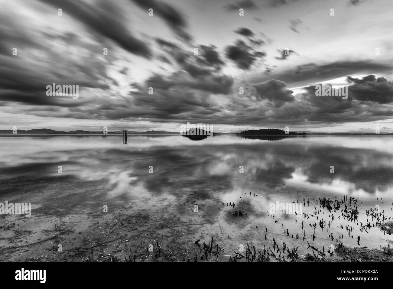 Perfetta e simmetrica nuvole e isole riflessioni su un lago, rendendo le forme astratte Foto Stock