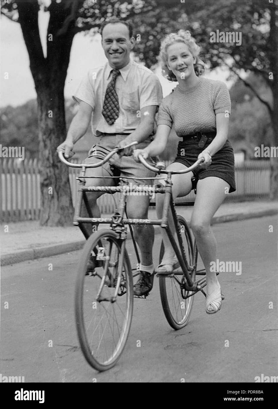 82 Un uomo e una donna su un Malvern Star affiancate biciclette tandem, c. 1930s, dalla cappa di Sam Foto Stock