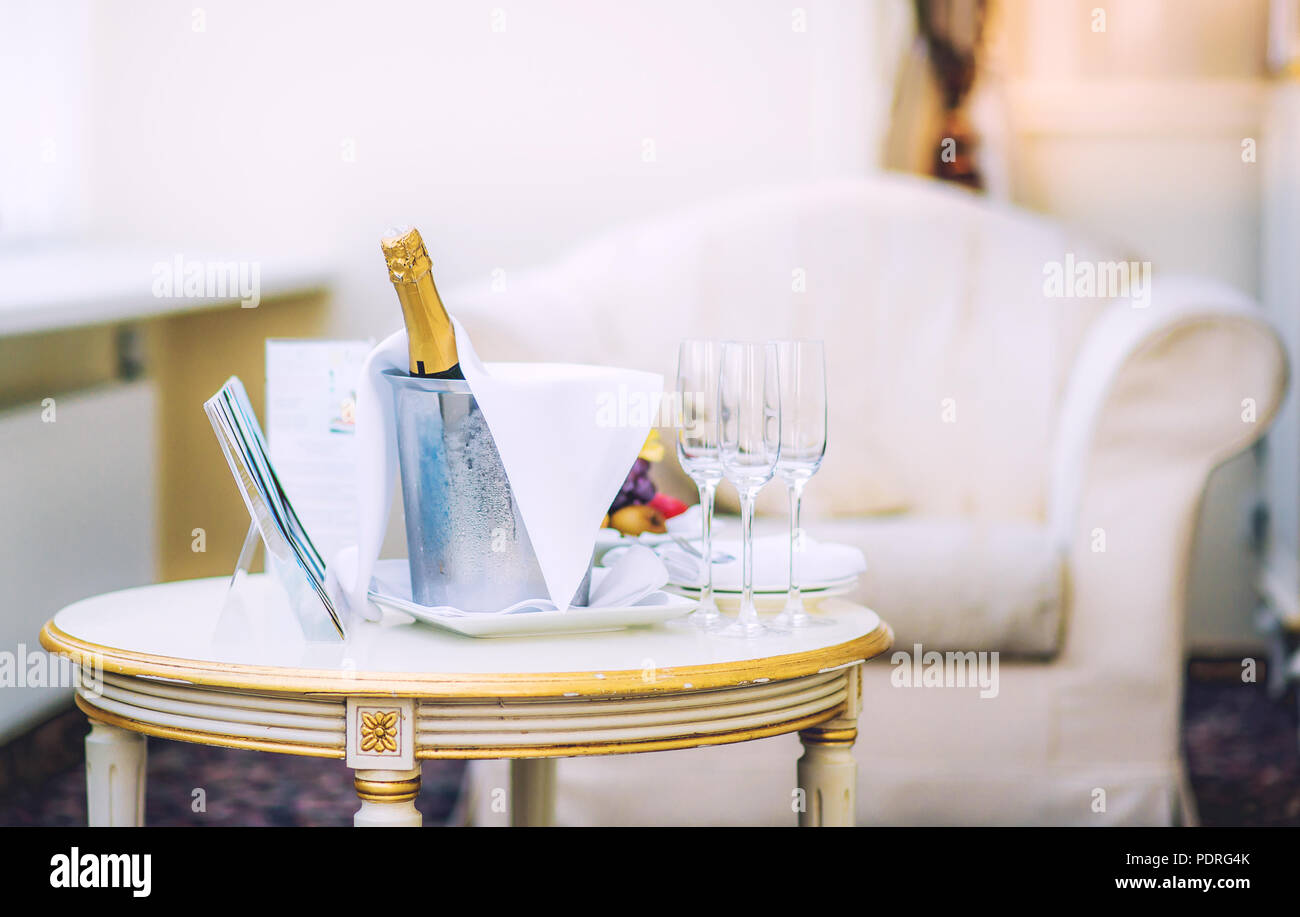 Bottiglia di champagne e bicchieri su un tavolo nella stanza dell'hotel Foto Stock