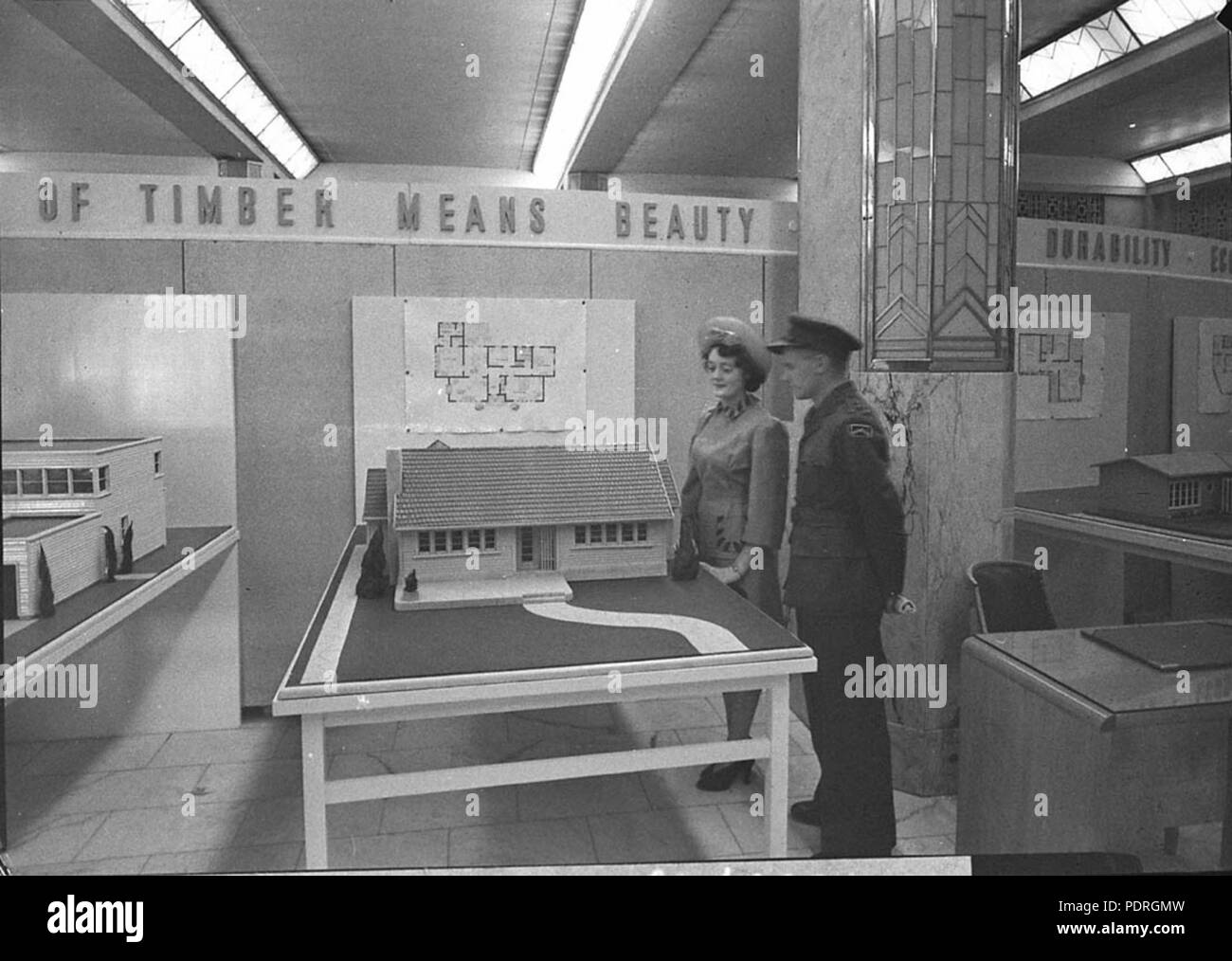 135 13383 SLNSW Airman e donna ammirare un modello di un cottage di legno mostra Case Foto Stock