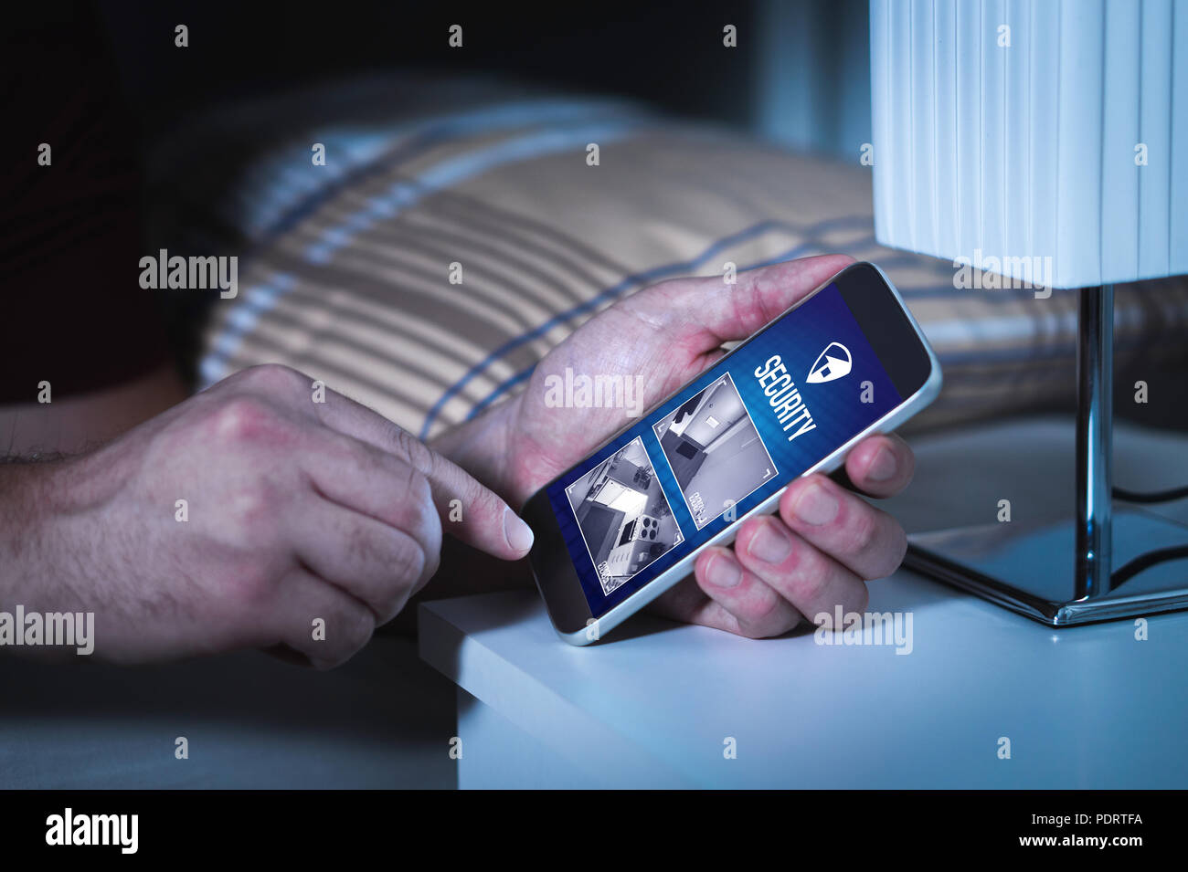 Uomo che per mezzo di un sistema di sicurezza domestica e l'applicazione nello smartphone. Guardando la protezione e la sorveglianza della telecamera riprese dal vivo all'interno di una casa o un appartamento. Foto Stock