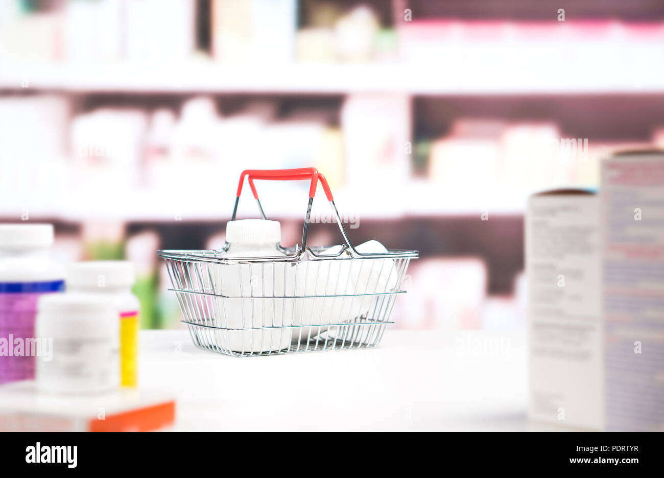 Farmacia con farmaci e ripiani. Carrello della spesa pieno di medicina e flaconi portapillole sul contatore in farmacia. Foto Stock