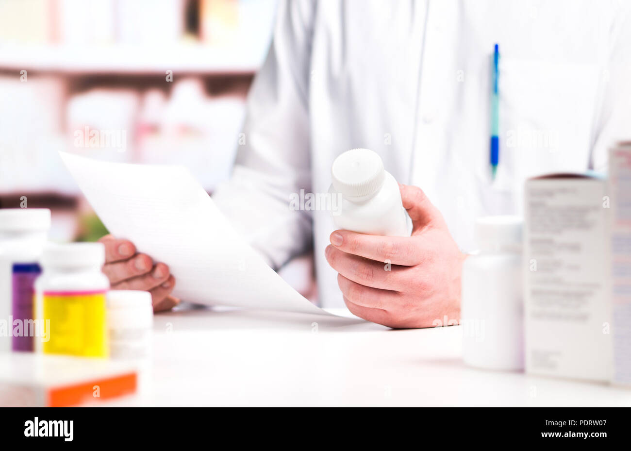 Il farmacista prescrizione di lettura con la medicina e la pillola bottiglia in mano in farmacia. Medico nella farmacia contatore. Foto Stock