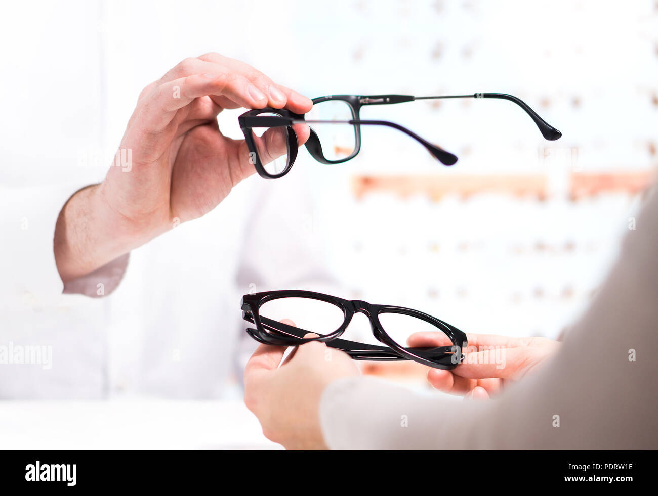 Ottico dando nuovi occhiali per il cliente per il test e il tentativo. Occhio medico paziente mostrando lenti per occhiali store. Foto Stock
