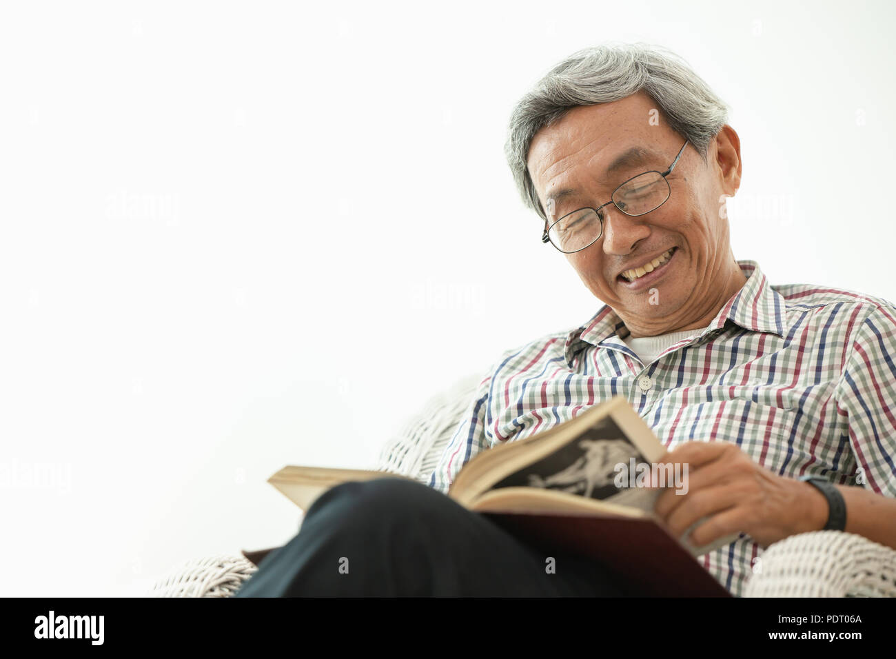 Asian anziani sorriso mentre leggendo in camera bianca Foto Stock