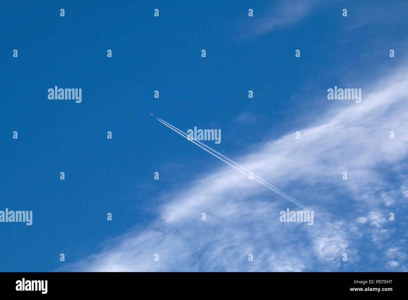 Piano, contrail e nubi Cirrocumulus contro il cielo blu. Foto Stock