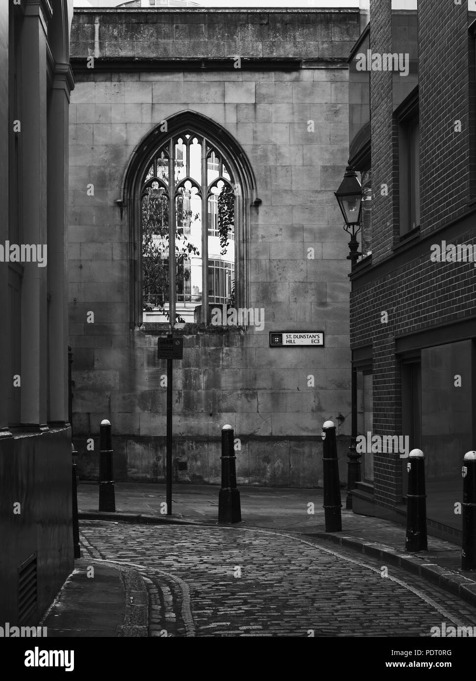 Immagine in bianco e nero di strada atmosferica con ciottoli a Londra. Muro di pietra con stile gotico finestra Foto Stock