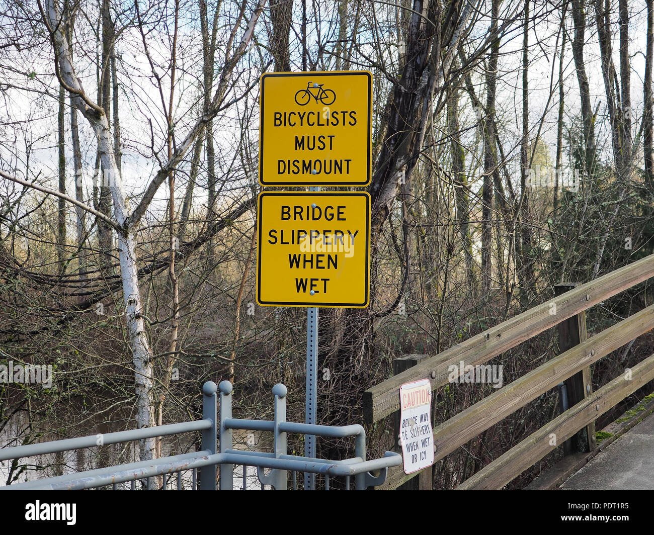 Segni 'I Ciclisti devono smontare' e 'il pattino del ponte quando bagnato' in Bothell, WA, USA Foto Stock