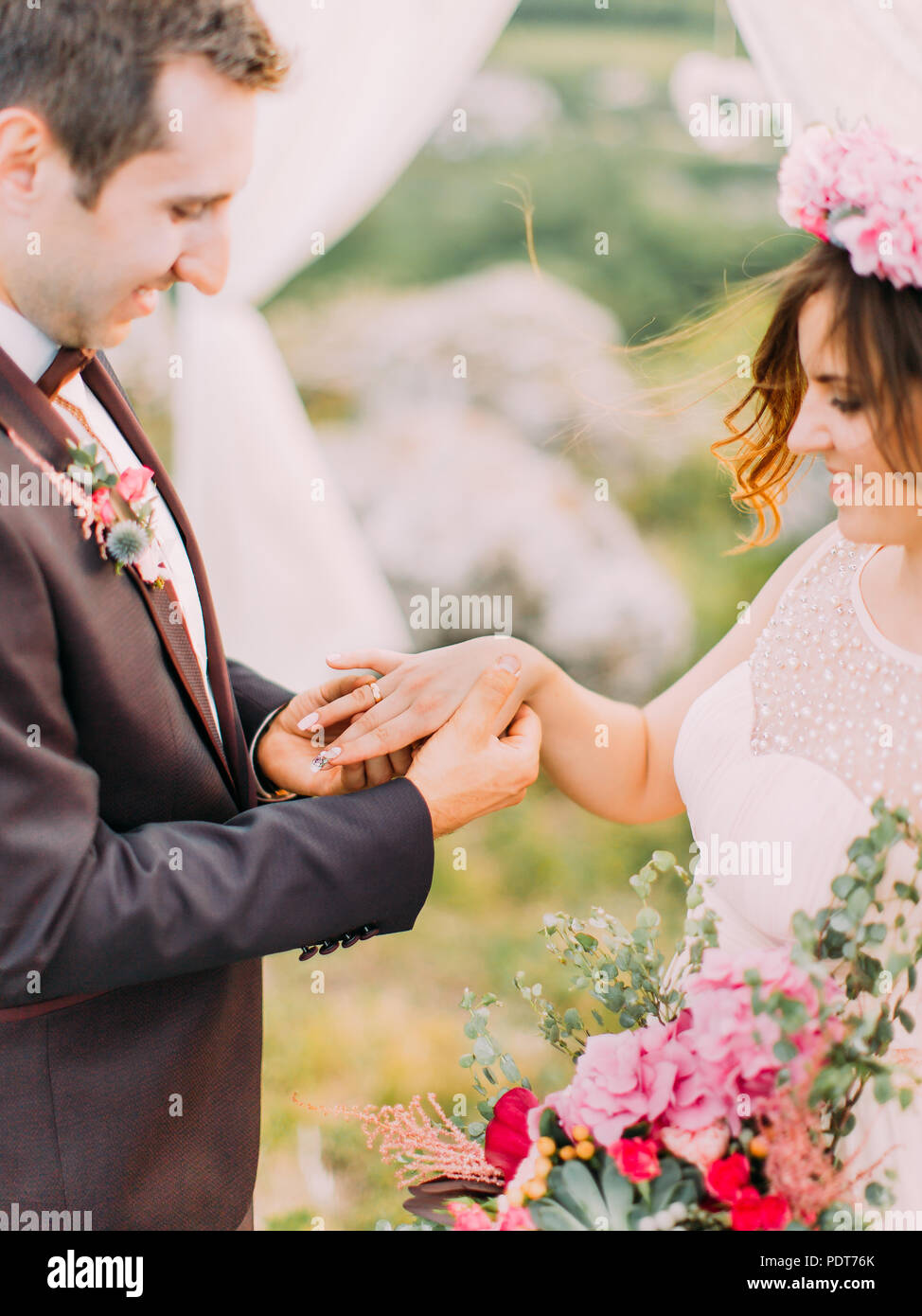 Vista ravvicinata del groom ponendo l'anello nuziale sulle mani della sposa durante la cerimonia di nozze. Foto Stock