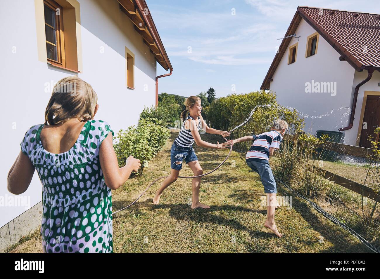 I bambini si divertono con spruzzi d'acqua. I fratelli sul cortile della casa durante il giorno d'estate. Foto Stock