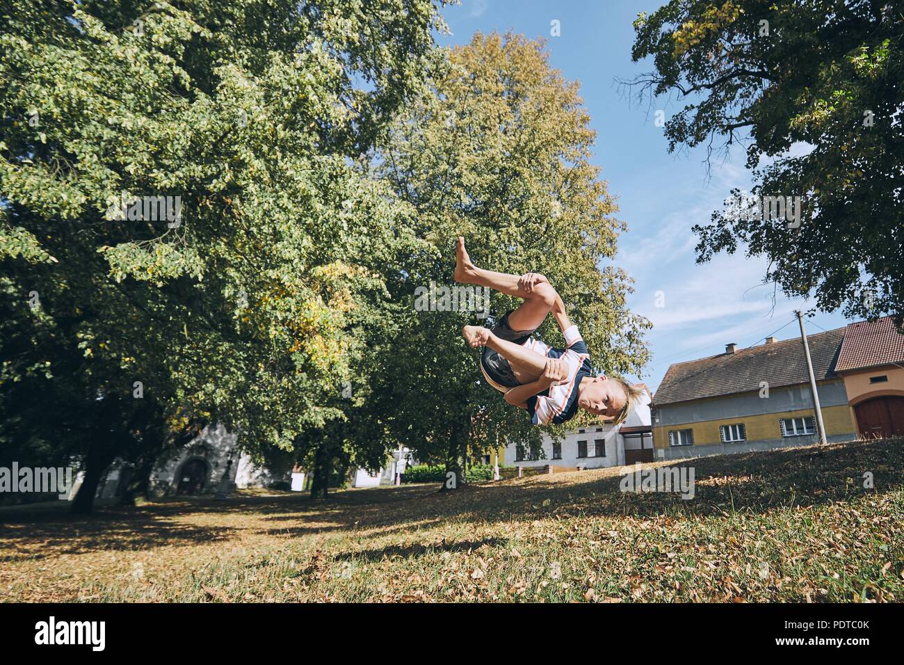 Ragazzo praticante runnuing libero nel parco pubblico e saltando capovolto. Foto Stock