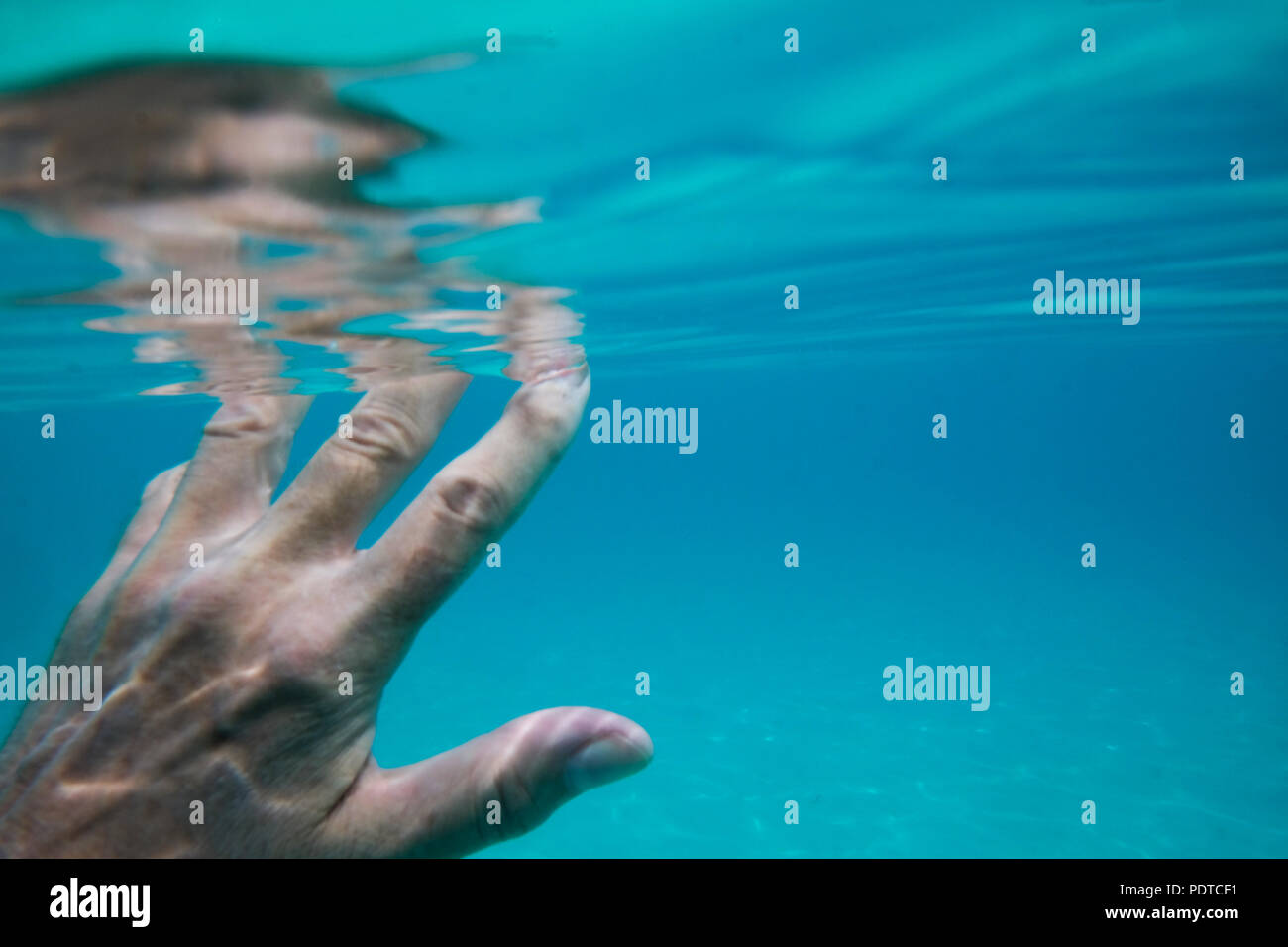 A cinquanta anni di donna metà mano sott'acqua in mare e le dita sopra l'acqua del mare è molto blu Foto Stock