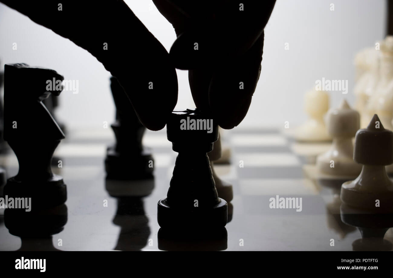 Partita scacchi a personaggi viventi di essere riprodotti. Movimento del dito pezzo degli scacchi in silhouette. Foto Stock