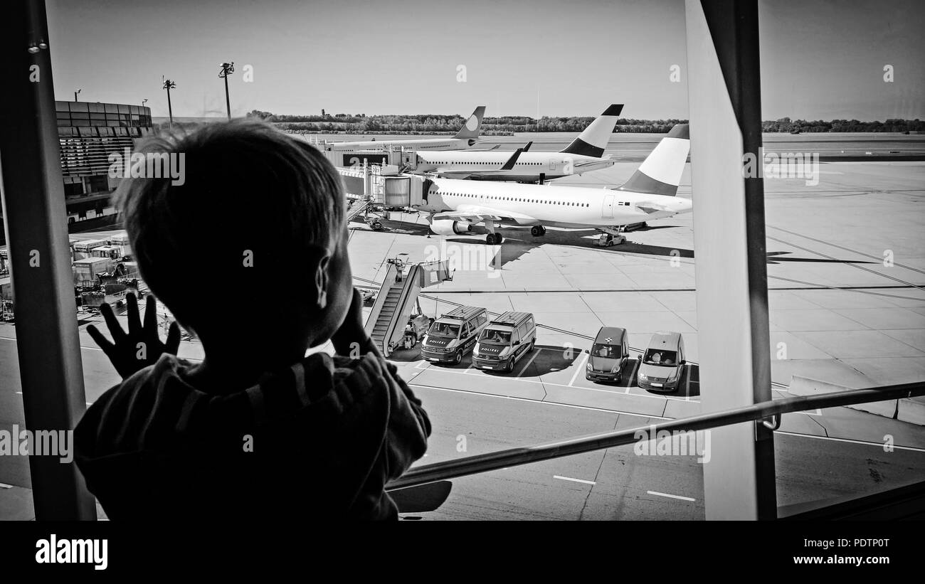 2 anno di old boy longingly orologi aerei attraverso la finestra di terminal di un aeroporto (uso commerciale) Foto Stock