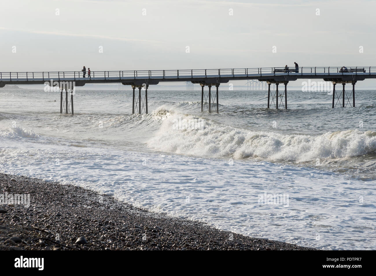 Onde che si infrangono sulla spiaggia accanto al molo cambs, North Yorkshire, Inghilterra. Foto Stock