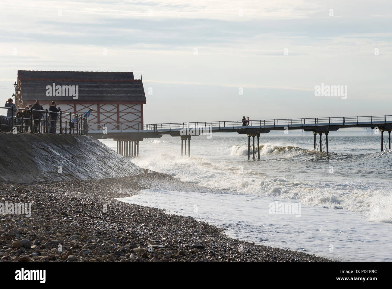 Guardare la gente di onde che si infrangono sulla spiaggia di cambs, North Yorkshire, Inghilterra. Foto Stock
