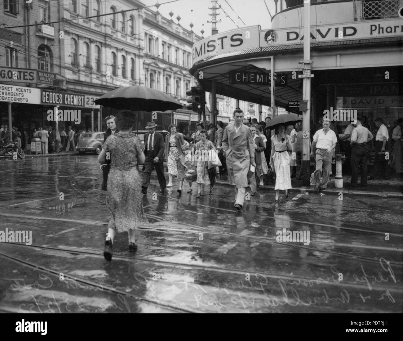 203 StateLibQld 1 107360 persone attraversando George Street sotto la pioggia, Brisbane, 1952 Foto Stock