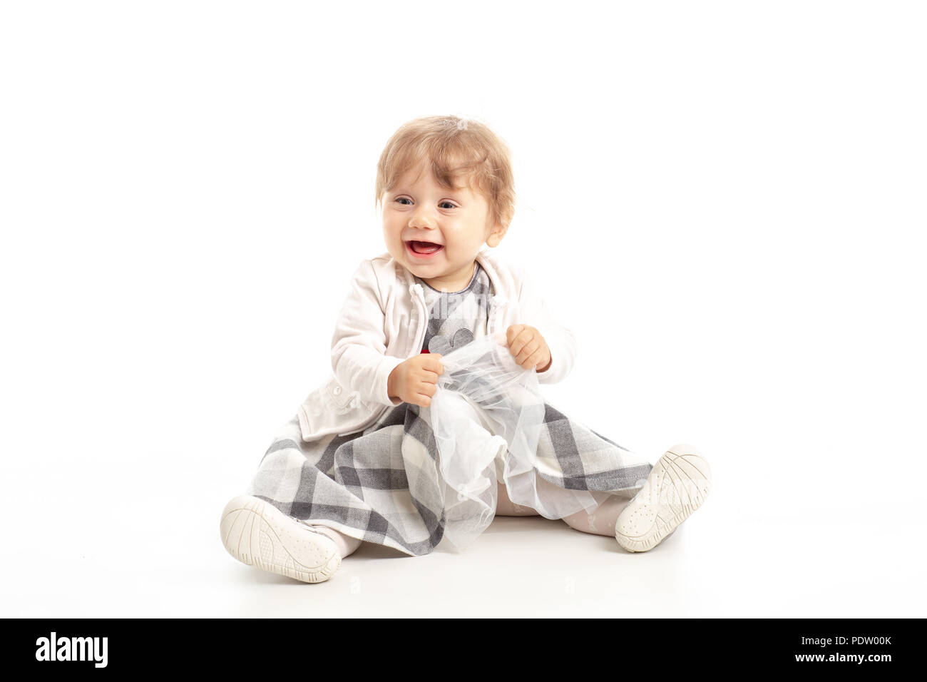 Eleganti bambina 1 anno vecchio seduto sul pavimento in studio. Sfondo bianco. Foto Stock