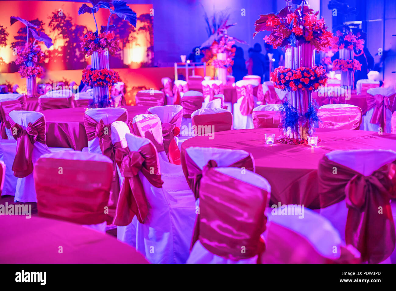Indian ricevimento di nozze, tavolo da pranzo e sedie impostazioni decorare con vaso di fiori colorati, illuminazione a LED per la decorazione tradizionale indiana sangeet Foto Stock