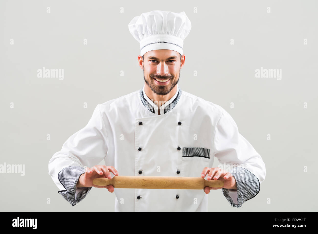 Ritratto di chef holding mattarello su sfondo grigio. Foto Stock