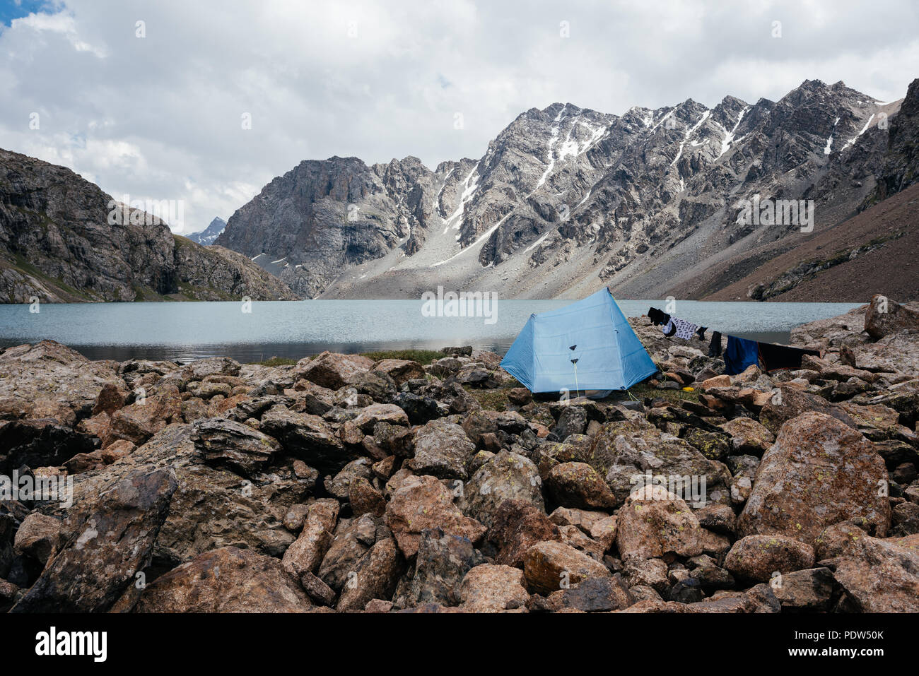 Camping con una piccola tenda blu in Piazza Tian Sham montagne, Kirghizistan. Tian Shan montagne sono alcuni dei luoghi più belli per fare trekking. Foto Stock