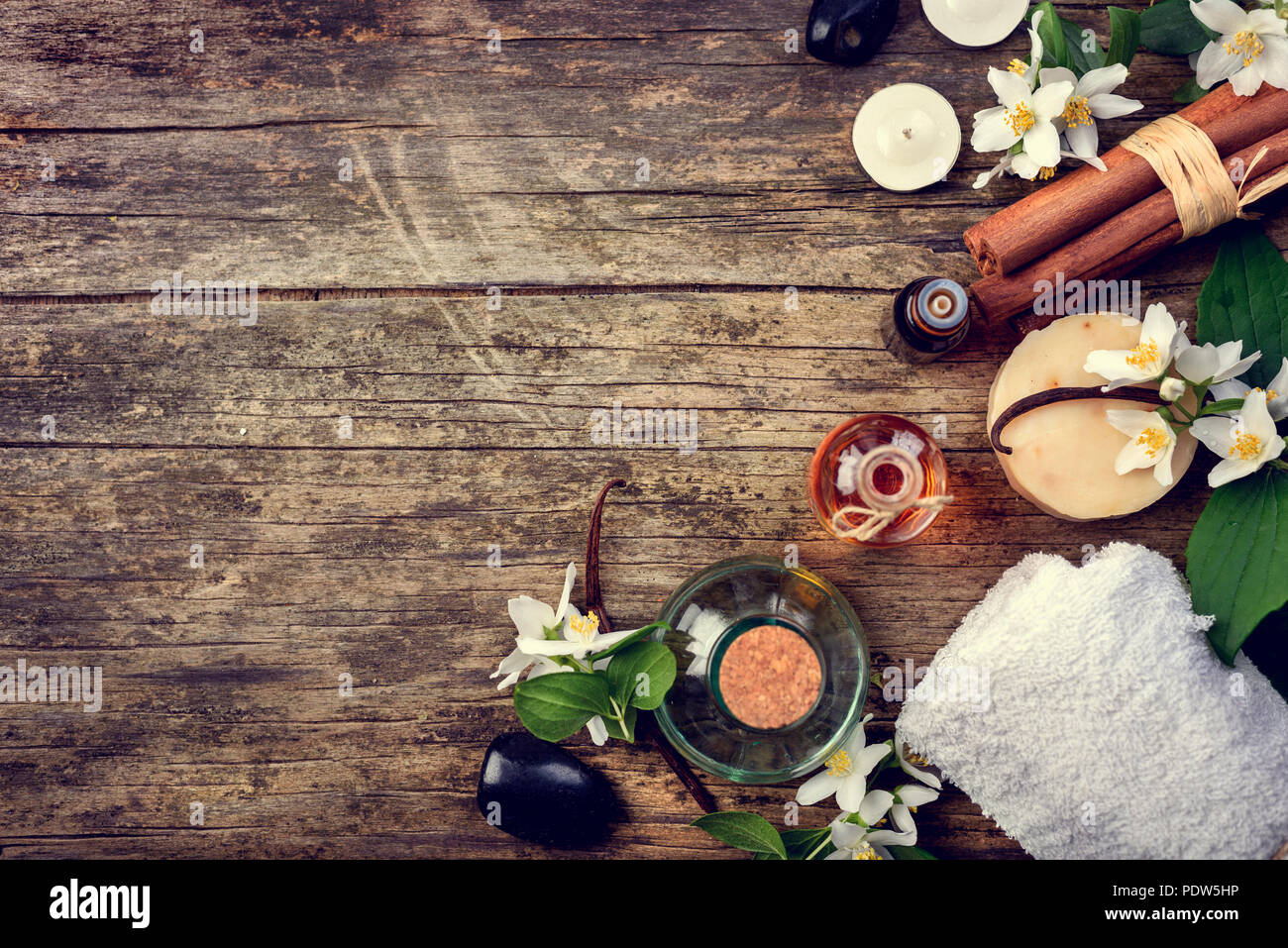 Oli essenziali con gelsomino, cannella e vaniglia su tavola in legno rustico, stile retor immagine. Foto Stock