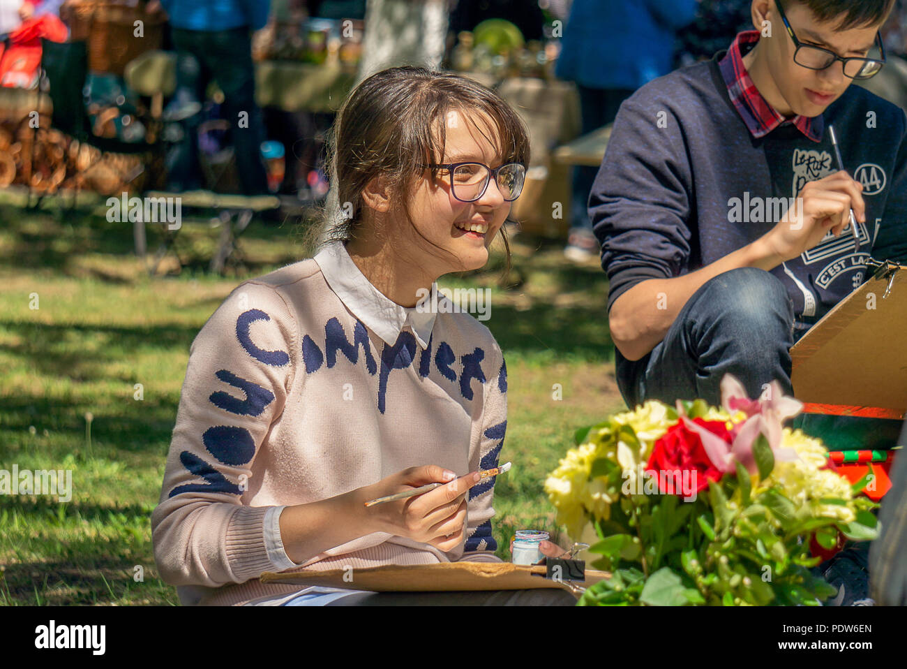 DZERZHINSK, RUSSIA - 26 MAGGIO 2018: Felice giovane ragazza pittura su carta con vernici acquerello. Faccia felice sorridente. Classe master open air. Foto Stock