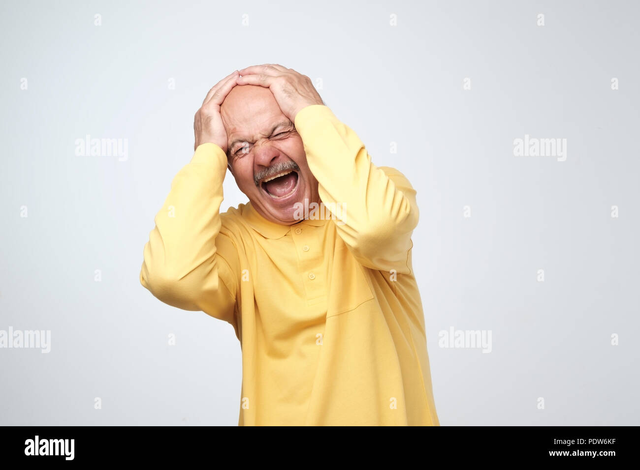 Stop che rumore forte concetto. Uomo maturo in giallo tshirt soffre di musica ad alto volume e dolore urlando cercando di collegare le orecchie contro uno sfondo grigio. Sa Foto Stock Stop che rumore forte concetto. Uomo maturo in giallo tshirt soffre di musica ad alto volume e dolore urlando cercando di collegare le orecchie contro uno sfondo grigio. Sa Foto Stock