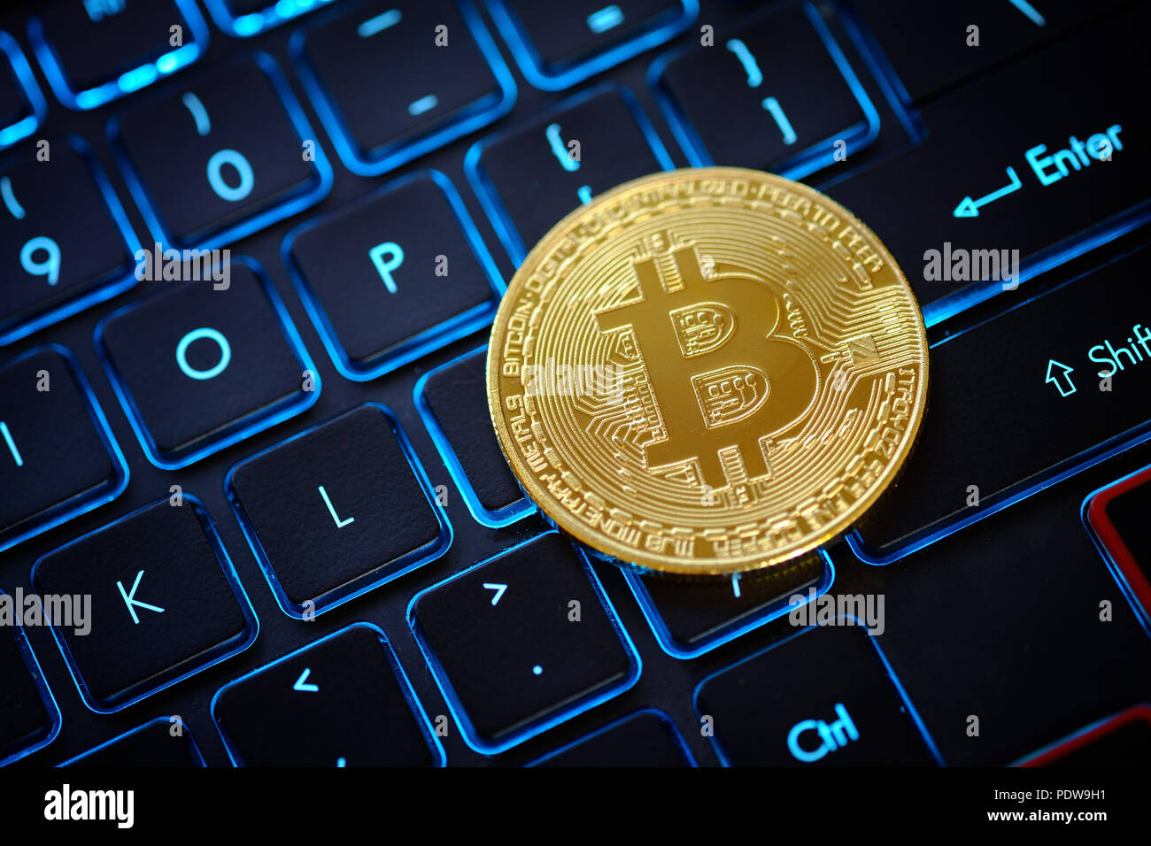 Golden Bitcoin come moneta crypto sulla parte superiore della tastiera illuminata Foto Stock