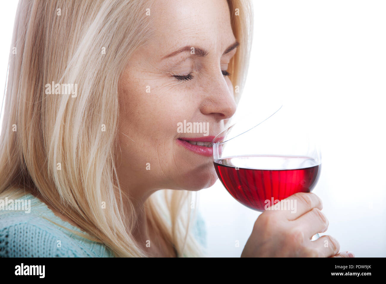 Bella donna di mezza età di bere il vino rosso con gli occhi chiusi a casa. Foto Stock