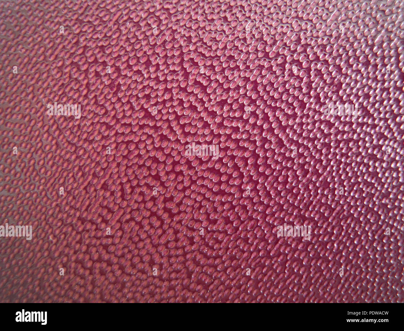 Texture di piccole bolle in un bicchiere di acqua con uno sfondo rosso sotto gli occhiali Foto Stock