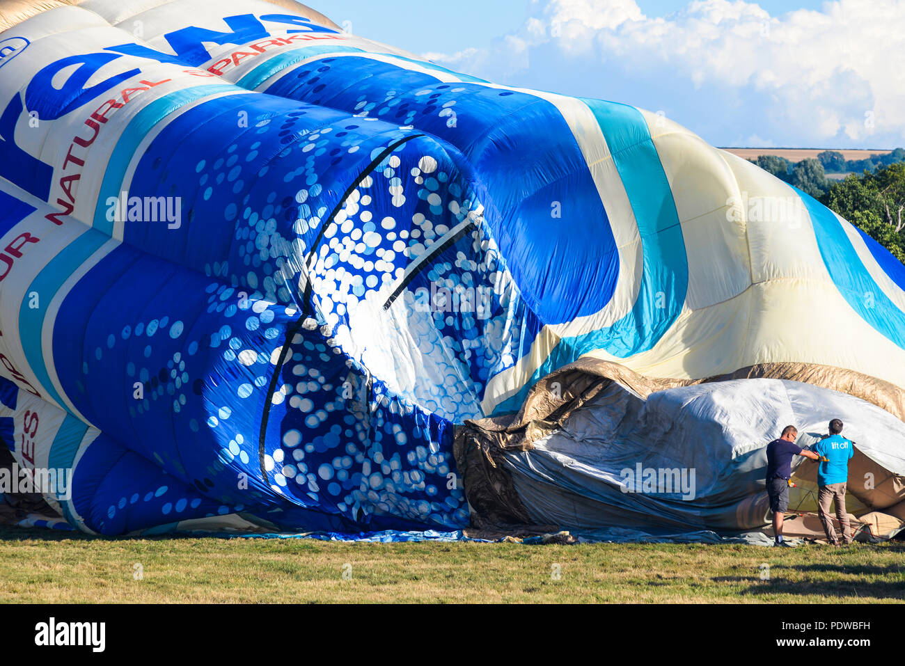 Grande mongolfiera durante il gonfiaggio sul terreno con la gente per la scala. Andrews può palloncino G-OFIZ costruito da Cameron Balloons Foto Stock